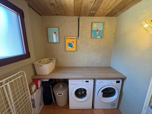 Un área de lavandería con dos lavadoras, un tendedero y una ventana.