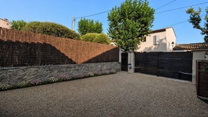 A gravel driveway leading to a gated entrance with a tree and a stone wall. - Casa Solea - Gulf of Saint-Tropez (Le Plan-de-la-Tour)
