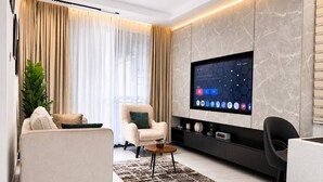 A modern living room with a flat-screen TV, a sofa, a chair, and a coffee table. - Uptown Homes Kampala (Kampala)