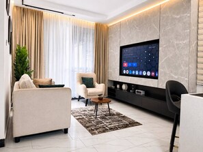 Una sala de estar moderna con una televisión de pantalla plana, un sofá, un sillón y una mesa de centro.
