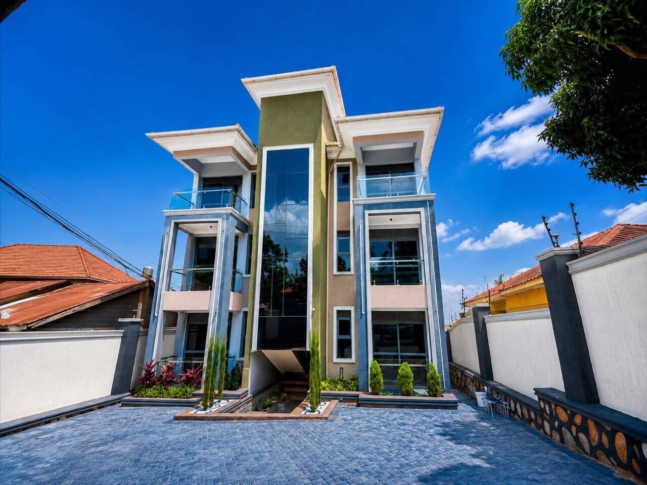 A modern multi-story building with a central staircase, large windows, and a paved courtyard.
