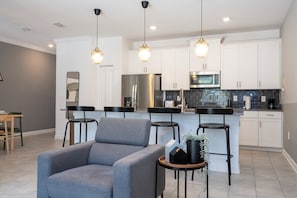 A modern kitchen with white cabinets, stainless steel appliances, and a central island with bar stools. - ☆☆☆☆☆Price Drop! OCT-NOV - 4BR ChampionsGate - Pool - Themed Rooms! 
☆☆☆☆☆ (Davenport)