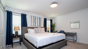 A modern bedroom with a large bed, bedside lamps, a desk, and a potted plant. - Relaxing 4BR ChampionsGate Getaway - Private Pool, BBQ & Family Comfort (Davenport)