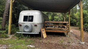 Un espacio al aire libre cubierto con una autocaravana antigua estacionada debajo.