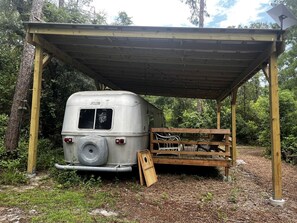 A covered outdoor area with a vintage camper parked underneath.