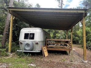 Un espacio al aire libre cubierto con una autocaravana antigua estacionada debajo.