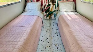 Una habitación pequeña y acogedora con dos camas, un ventanal y un mural en la pared.