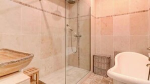 Ein Badezimmer mit einer gläsernen Dusche, einer freistehenden Badewanne und einem großzügigen Waschbecken.
