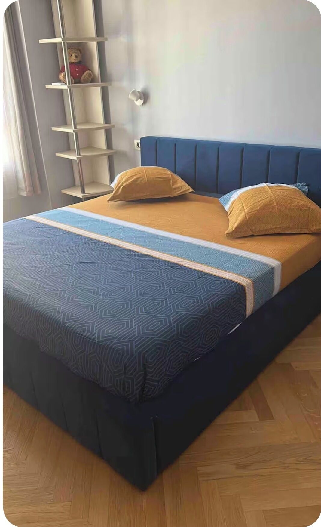 Un lit avec une couvre-lit à motifs, deux oreillers et une tête de lit.