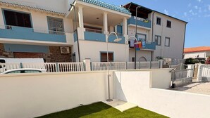 Een modern gebouw met twee verdiepingen, een plat dak, een balkon en een verzorgd gazon.