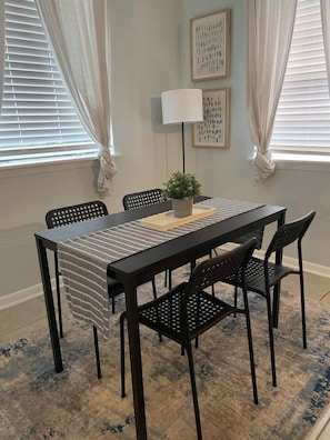 A dining area with a table, chairs, a lamp, and artwork on the walls.
