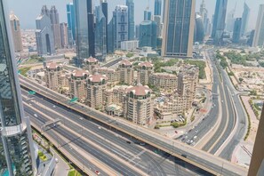 A high-rise building with multiple floors, surrounded by a busy highway and other high-rise buildings. - Spacious Studio Fashion Ave Dubai Mall Burj view (Dubai)