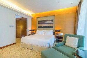 A hotel room with a large bed, a green sofa, a painting on the wall, and a nightstand with lamps. - Spacious Studio Fashion Ave Dubai Mall Burj view (Dubai)