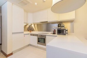 A modern kitchen with white cabinetry, stainless steel appliances, and a white countertop. - Spacious Studio Fashion Ave Dubai Mall Burj view (Dubai)