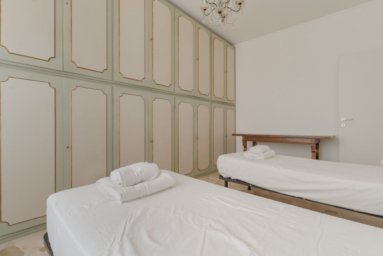 Une chambre avec deux lits, une tête de lit en bois et une armoire ornée d’un motif à panneaux verts.