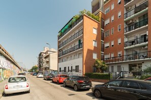 A multi-story residential building with balconies, parked cars, and a graffiti-covered wall. - Spacious apartment of approximately 100 sqm, accommodating up to 7 people, located on the fifth and top floor of a building with an elevator (NOT accessible to people with disabilities).The property is situated in the Cimiano district, just a 5-minute wa (Milan)