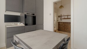 A modern kitchen with grey cabinetry, a built-in oven, and a dining area with a table and chairs. - Spacious apartment of approximately 100 sqm, accommodating up to 7 people, located on the fifth and top floor of a building with an elevator (NOT accessible to people with disabilities).The property is situated in the Cimiano district, just a 5-minute wa (Milan)