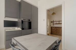 A modern kitchen with grey cabinetry, a built-in oven, and a dining area with a table and chairs. - Spacious apartment of approximately 100 sqm, accommodating up to 7 people, located on the fifth and top floor of a building with an elevator (NOT accessible to people with disabilities).The property is situated in the Cimiano district, just a 5-minute wa (Milan)