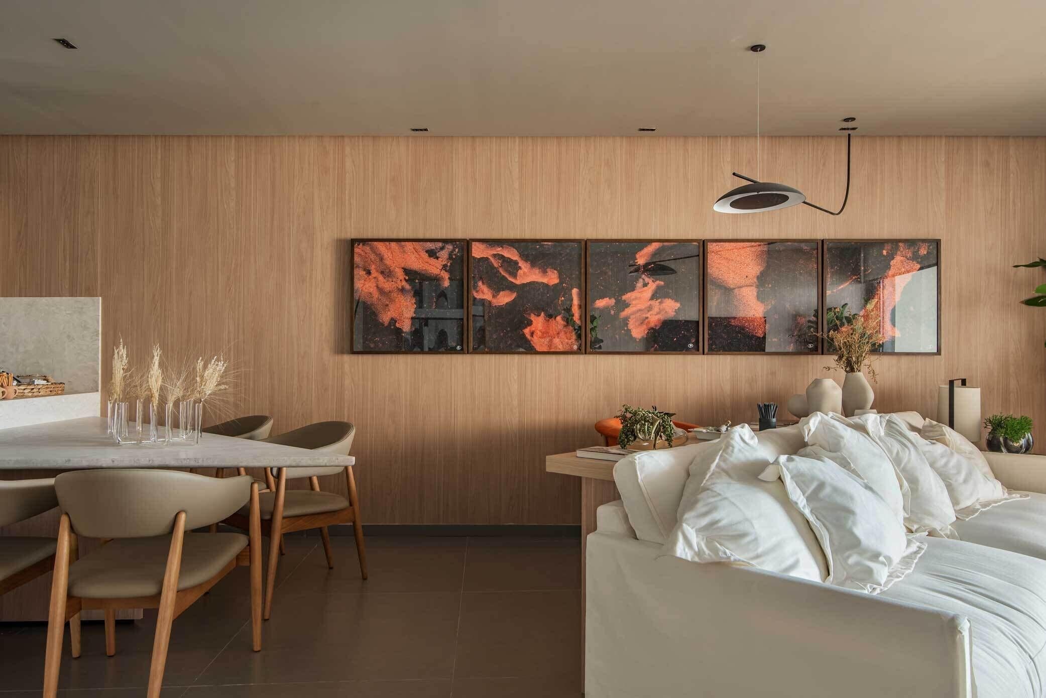 Uma sala de estar moderna com um sofá branco, uma área de jantar com cadeiras e uma obra de arte pendurada na parede.