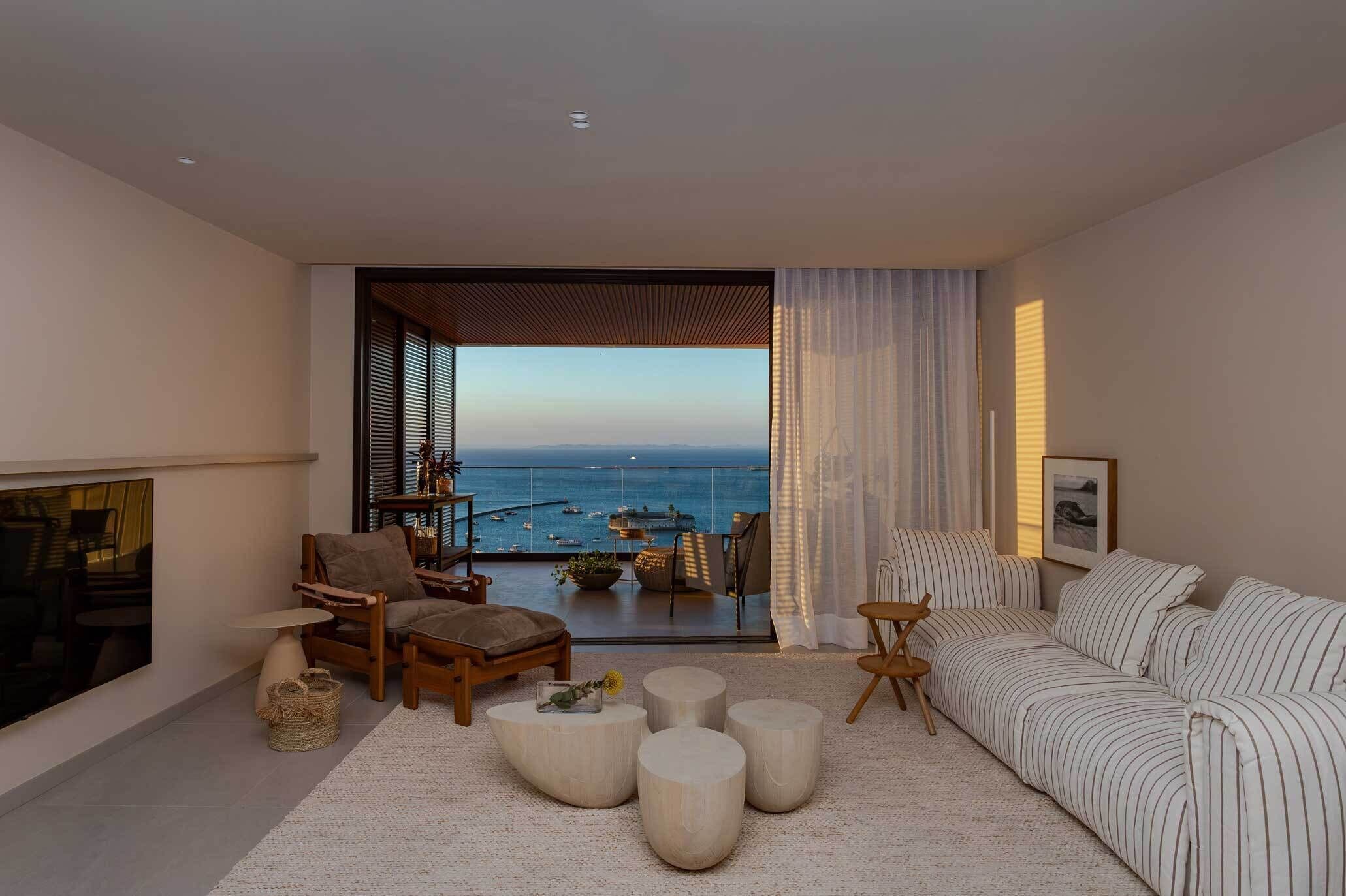 A modern living room with a view of the sea, a sofa, a chair, and a small table.