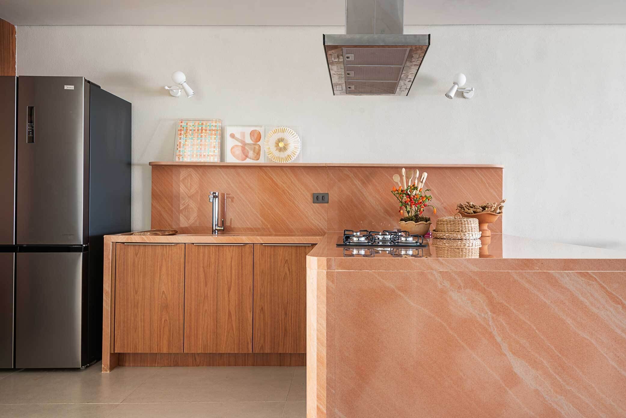 Una cocina moderna con refrigerador empotrado, gabinetes de madera, estufa de acero inoxidable y encimera de mármol.