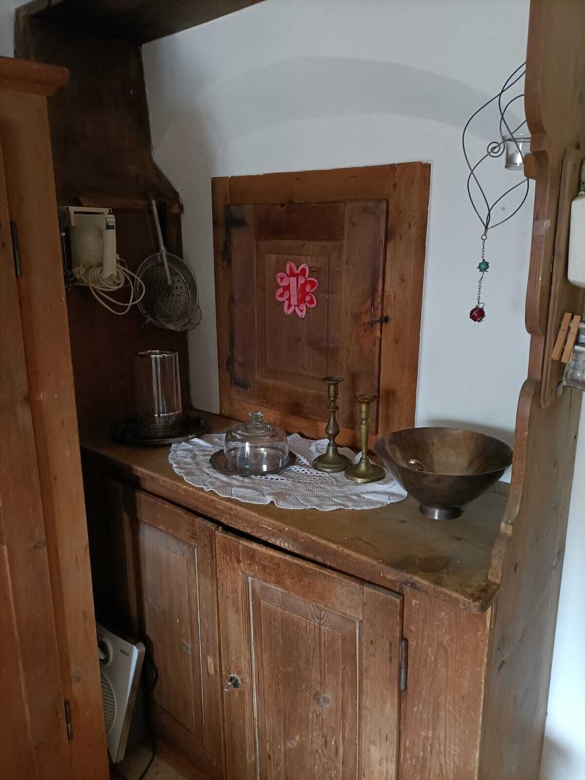 Une cuisine en bois avec un meuble en bois, un saladier en métal, un récipient en verre et un pichet en métal.
