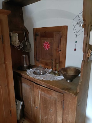 Eine Holz-Küche mit Holzkabinett, einer Metallschüssel, einem Glasbehälter und einem Metallkrug.