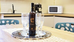 Keittiössä on tarjotinalusella viinipullo ja lasit, mikroaaltouuni ja pesuallas.