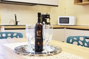 Eine Weinflasche auf einem Tablett mit Gläsern, eine Mikrowelle und ein Spülbecken in einer Küche.