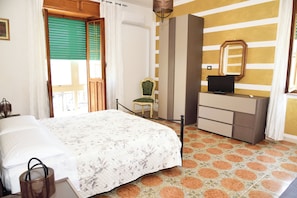 Ein Hotelzimmer mit Bett, Sessel, Schminktisch und Fernseher.