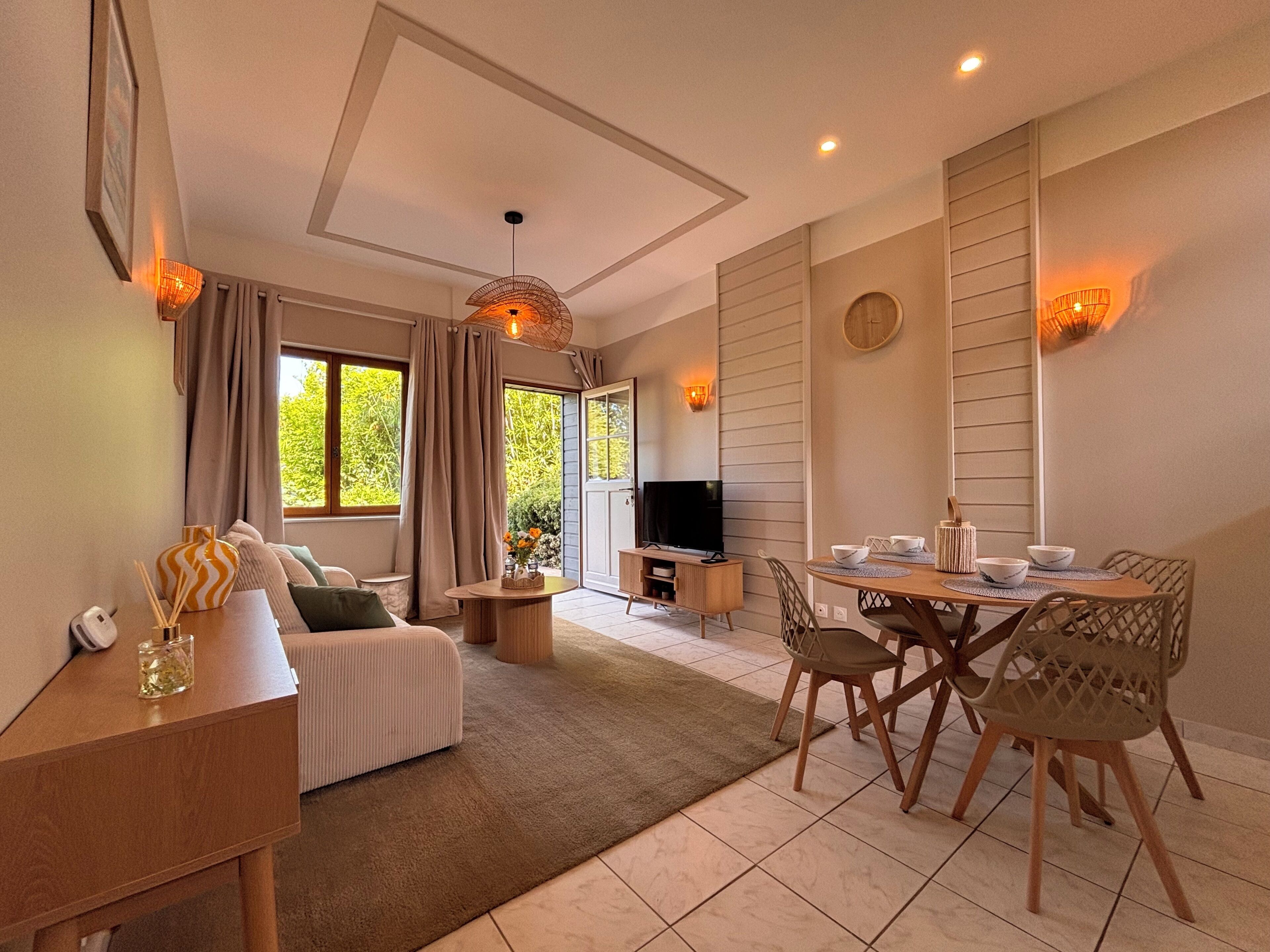 Ein modernes Wohnzimmer mit Sofa, Couchtisch, Fernseher und Essbereich mit Stühlen und Tisch.