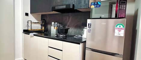 A modern kitchen with a stainless steel refrigerator, a microwave, and a black cabinet above the counter.