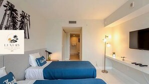 Ein Hotelzimmer mit einem Bett, einem Fernseher, einem Nachttisch und einem Beistelltisch.