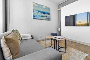 A modern living room with a sofa, a small table, and a painting on the wall. - One Rosebank 151 (Johannesburg)