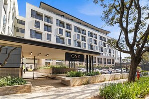 A modern hotel with a prominent 'ONE' sign, a covered entrance, and a parking area with cars. - One Rosebank 151 (Johannesburg)