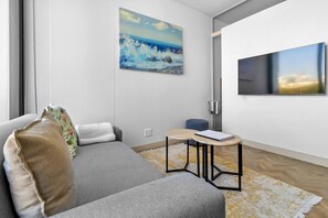 Ein modernes Wohnzimmer mit einer Couch, einem kleinen Tisch und einem Bild an der Wand.