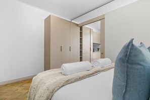 A bedroom with a bed, a wardrobe, and a mirror. - One Rosebank 151 (Johannesburg)