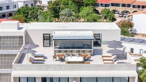 Una terrazza sul tetto con posti a sedere all'aperto, una piscina e pannelli solari.