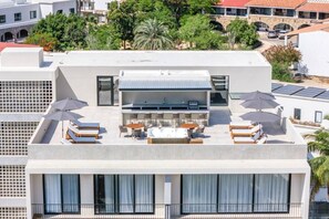 A rooftop terrace with outdoor seating, a pool, and solar panels. - Coyote Tower 201 | Luxury Condo Walk to Marina (Cabo San Lucas)