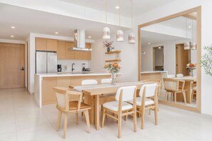 A modern kitchen with a central island, wooden chairs, and pendant lights. - Coyote Tower 201 | Luxury Condo Walk to Marina (Cabo San Lucas)