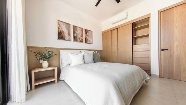 Una camera da letto con un letto, un comodino, una pianta in vaso, decorazioni alle pareti, un armadio e scaffali a muro.