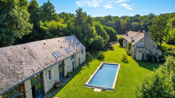A large house with a swimming pool, surrounded by lush greenery and trees.
