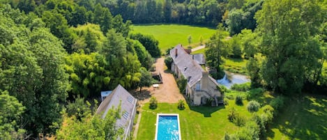 Une vaste propriété dotée d’une piscine, de plusieurs bâtiments et entourée d’une forêt.