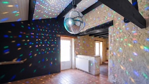 A spacious room with a disco ball, tiled floor, and a stone wall. - So Villa Chez Penet (16) - Outdoor Pool - Beach Volleyball - 1 hour from Bordeaux - Sleeps 30. (Berneuil)