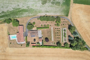 An aerial view of a property with a swimming pool, multiple buildings, and a large field.