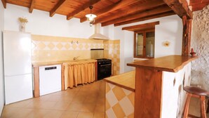 A kitchen with wooden beams, a tiled backsplash, a sink, a stove, and a refrigerator. - So Villa Chez Penet (16) - Outdoor Pool - Beach Volleyball - 1 hour from Bordeaux - Sleeps 30. (Berneuil)