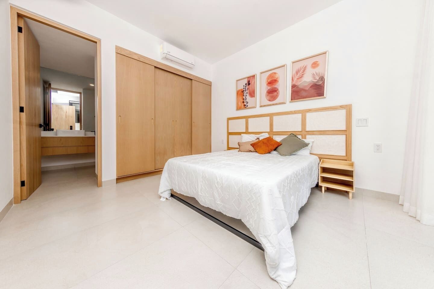 A bedroom with a bed, a wardrobe, a bedside table, and a wall-mounted air conditioner.
