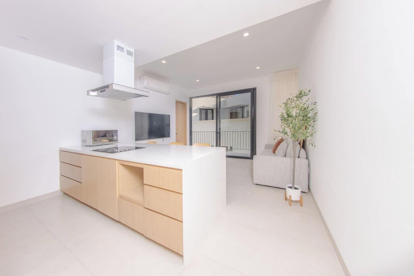 A modern kitchen with a central island, built-in appliances, and a view to a balcony.