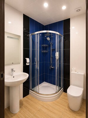 A modern bathroom with a glass-enclosed shower, a white sink, and a toilet.