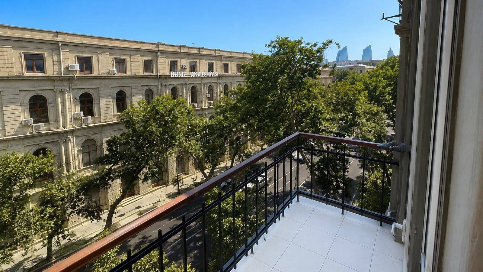 Uma varanda com vista para um edifício histórico com janelas em arco e uma placa que diz 'Doniz Akaleem Yasa'.